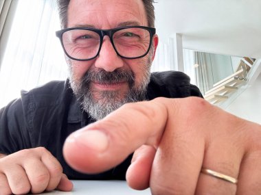 Diz üstü bilgisayar ya da telefon kamerası erişkin bir adamın parmaklarıyla tıklamaya hazır olduğunu gösteriyor ve gözlük takarken görme sorunu yaşıyor. Yaşlı insanlar ve gözlük görme sorunu. Web sayfasında çok küçük yazı tipleri kullanmak