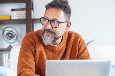 Evde dizüstü bilgisayarla çalışan yetişkin bir adamın ön görüntüsü. Çevrimiçi bilgisayar teknolojisi bağlantısı olan profesyonel serbest çalışan insanlar. Net konsept yaşam tarzına göz atmak ve araştırmak. Uzak çalışma