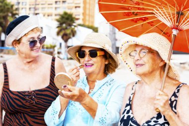 Yazın gülümseyen ve poz veren bir grup kadın arkadaş arkadaşça boş zamanlarında birlikte fotoğraf çekiliyorlar. Renkli aksesuarlar ve güneş gözlükleri. Tatil tatili yaşlı insanlar bayan bayanlar