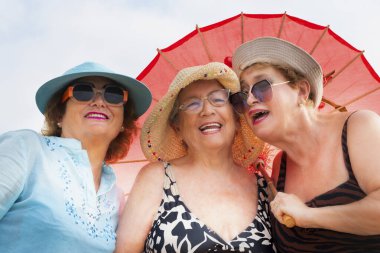 Yazın gülümseyen ve poz veren bir grup kadın arkadaş arkadaşça boş zamanlarında birlikte fotoğraf çekiliyorlar. Renkli aksesuarlar ve güneş gözlükleri. Tatil tatili yaşlı insanlar bayan bayanlar