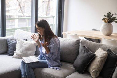 Gülümseyen kadın dizüstü bilgisayar kullanıyor, evdeki koltukta oturuyor, güzel kız sosyal ağlarda sohbet ediyor ve arkadaşlarıyla gülüyor. Teknoloji ve arkadaşlık kavramı..