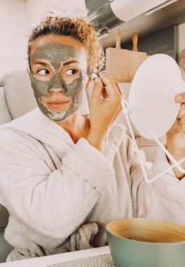  Güzel, yetişkin bir kadın günlük cilt bakımı rutiniyle meşgul. Kırışıklıklar için doğal yeşil maske ve karavanın içinde ayna tutan sağlıklı gözler kullanıyor. Göçebe minibüs hayatı ve kendini sevme