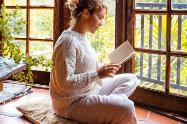 Doğal yaşam tarzı ve bilgi. Zen gibi düşünceli bir şekilde yerde oturan bir kadın. Sağlıklı yaşam tarzı ve eğitim insanları yaşam konsepti. Evin içinde keyif çatmak ve dinlenmek.