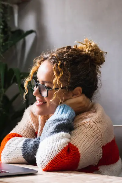 stock image modern casual female using computer at home watching movie or reading email smiling and relaxing. Indoor technology wireless leisure activity online. Adult woman wearing glasses to read contents