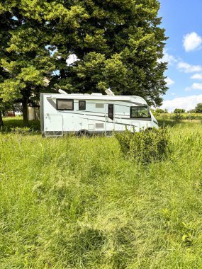 Kırsal kesimde çimlerin üzerine park edilmiş büyük bir karavan. Özgürlük ve seyahat alternatif yaşam tarzı. Yaz tatili için nakliye aracı. Vanlife ve grid dışında yaşamak