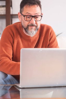 Evde dizüstü bilgisayarla çalışan yetişkin bir adamın ön görüntüsü. Çevrimiçi bilgisayar teknolojisi bağlantısı olan profesyonel serbest çalışan insanlar. Net konsept yaşam tarzına göz atmak ve araştırmak. Uzak çalışma