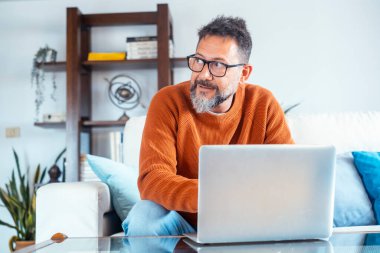 Evde dizüstü bilgisayarla çalışan yetişkin bir adamın ön görüntüsü. Çevrimiçi bilgisayar teknolojisi bağlantısı olan profesyonel serbest çalışan insanlar. Net konsept yaşam tarzına göz atmak ve araştırmak. Uzak çalışma
