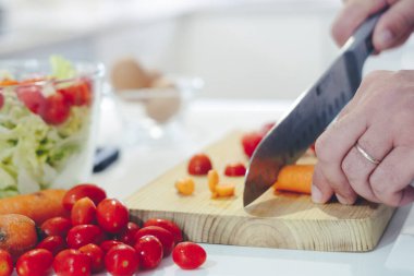 Evde taze çiğ sebze doğrayan bir bıçakla şef. Evde pişirici sağlıklı sebze yemeği yapıyor, sebzeleri doğruyor - yiyecek. 