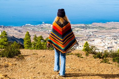 Muhteşem sahil manzarasına hayran olmak için uçuruma doğru yürüyen turist ve gezginin arka görüntüsü. Seyahat yeri manzaralı yer konsepti. Bir kadın tek başına dışarıda boş vakit geçirmekten hoşlanıyor. Özgürlük yaşam tarzı