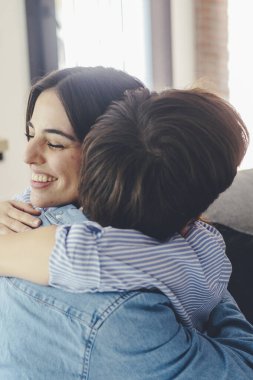 Kanepede oturmuş birbirlerine mutlu bir şekilde sarılan gülümseyen çift. Aşk ve mutluluk kavramı