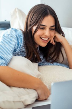 Güzel, mutlu bir kadın çalışıyor ya da dizüstü bilgisayarında komedi filmi izliyor. Evde yatakta yatıyor..