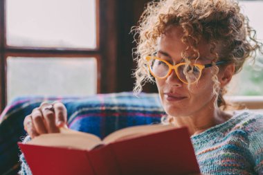 Evde oturan ve evde kitap okuyan bir kadın evde boş boş vakit aktivitesi yapıyor. Çalışan ve roman okuyan sakin kadınlar. Gözlük takıyordu. Bekar kadın yaşam tarzı. Pazar günü ve tatil