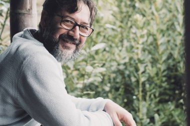 Mutlu ve neşeli genç bir adamın terasta dinlenerek evin dışında eğlenen portresi. Keyifli insanlar tatilde ya da evde boş vakitlerinde. Gözlüklü, sakallı, erkek.