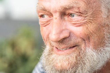 Gülümseyen ve dışarı bakan yaşlı adamın yan portresi. Yaşlanmış yetişkin erkek iç gözlem ifadesi. Düşünme ve düşünme son sınıf erkek insanlar dışarıda arka planda park ile