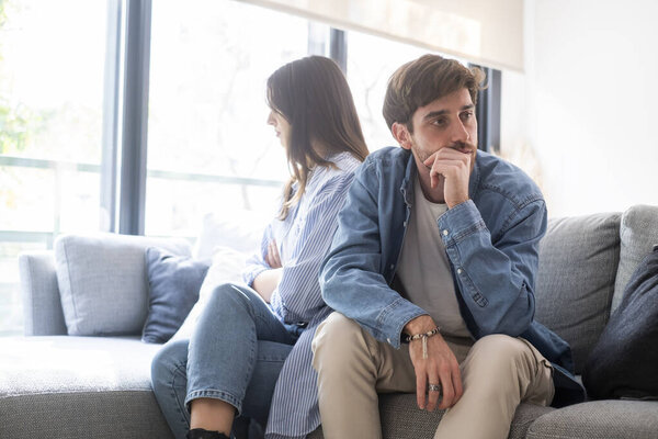Обручённая пара с проблемами в отношениях, сидящая на диване спиной друг к другу после ссоры, конфликты в браке, расстроенная пара после ссоры, принятие решения о расставании и разводе
