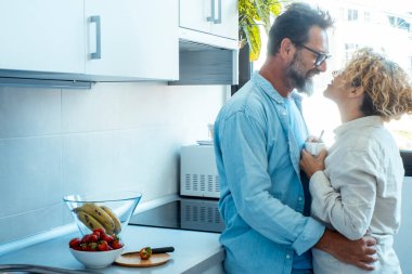 Romantizm ve iyi bir ilişki hayatı yaşayan insanlar bir yetişkin çiftin evde birbirlerine sarılıp öpüşmesi ve mutlu bir ifadeyle birbirlerine bakmaları. Bir erkek, içinde bir kadını sever ve kucaklar.