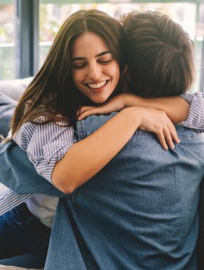 Mutlu çift, ayrıldıktan sonra birbirlerine sarılıyorlar. Sorunlar için uzun bir zaman. Yetişkin bir kadın erkek arkadaşını ya da kardeşini evdeki kanepede kucaklıyor. İnsanlarda sevgi ve duygu. Sarılma