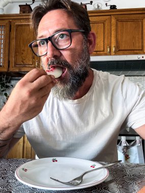 Yetişkin bir adam sağlıklı bir diyet yemeğini meyveli ve az miktardaki yiyecekle bitirir yağ azaltmak ve sağlık kazanmak için. Evde evde tek başına meyve yiyen yetişkin bir erkek portresi.