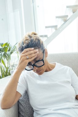 Sağlıksız, olgun bir kadın, evinde kanepede otururken gözleri kapalı otururken aşırı ısınmış hisseder, yaşlı bir kadın sağlık sorunları yaşar, migren olur, yüksek tansiyon olur, yaşlanma süreci ya da menopoz konsepti yaşar.