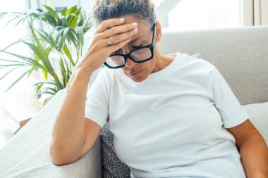 Mutsuz, üzgün, gözleri kapalı, şakaklara dokunan, yüksek tansiyon baş ağrısı, kronik migren, derin nefes alan, yorgun, genç bir bayanın acı çekmesi, kötü ve sağlıksız.