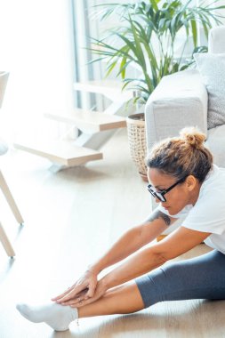 Yetişkin çekici kadın evde esneme egzersizleri yapıyor. Vücut ve sağlık hizmetleri kadın çalışanları günlük rutin egzersizlerini apartmanın zemininde yapıyorlar. Spor salonu, sağlıklı yaşam tarzı, yalnız ve mutlu bir bayan.