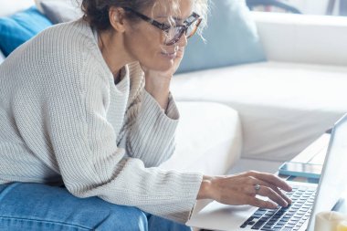 Evdeki kanepede oturan sakin kadın laptopunun önünde çalışıyor. Ev konseptinde çalış.