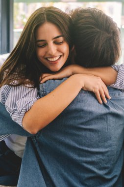 Evdeki kanepede oturmuş, ayrılık döneminden sonra kavuşmalarını kutlayan mutlu ve heyecanlı genç çift.. 