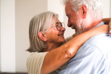 Neşeli, yaşlı bir çiftin kucaklaşması ve ömür boyu süren ilişkilerini evlerinde kutlaması. İkisi de sevecen gülümsemeler sergiliyor. Olgun ve sağlıklı yaşamlarından zevk alıyorlar ve derin bağlarını koruyorlar.
