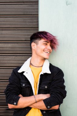 Young student in casual attire and colorful hair, laughing and enjoying the day while leaning against a wall in the city. Captures the essence of fun and trendy style in an urban setting clipart