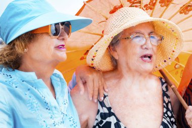 Yazın gülümseyen ve poz veren bir grup kadın arkadaş arkadaşça boş zamanlarında birlikte fotoğraf çekiliyorlar. Renkli aksesuarlar ve güneş gözlükleri. Tatil tatili yaşlı insanlar bayan bayanlar
