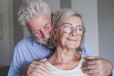 Boş vakitlerinde evde sevgi dolu kucaklaşan olgun bir çiftin yan görüntüsü. Yaşlı bir adam karısını arkadan tutar, onların romantik ve koruyucu bağlarını yakalar, son sınıfların sevgisini gösterir ve uzun süreli aşklarını gösterir.