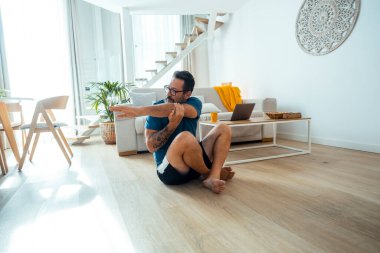 Orta yaşlı bir adam günlük ev antrenmanı rutinini uyguluyor. Gücünü, esnekliğini ve genel olarak sağlığını artırmak için, kişisel gelişime, zihinsel berraklığa ve spor yolculuğunun bir parçası olarak fiziksel sağlığına odaklanıyor.