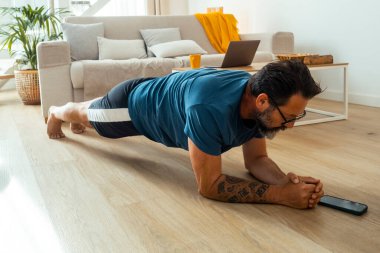 Adam günlük egzersizine katılıyor, temel gücünü arttırmak için günlük egzersizini kullanıyor, genel uygunluğunu arttırıyor ve disiplinli bir çabayla hem fiziksel hem de zihinsel sağlığını destekliyor.