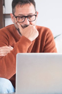 Dizüstü bilgisayara bakan konsantre olmuş yetişkin işadamı, İnternet 'te web sörfü bilgisi ya da ev ofisinde uzaktan çalışma, müşteri ya da çalışma ile uzaktan iletişim.