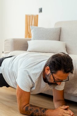 Orta yaşlı bir adam, ağırlık ve direnç bantlarını dayanıklılık eğitimi ve esneklik egzersizleri için kullanarak hem fiziksel hem de ruhsal sağlığını iyileştirmeyi hedefliyor.