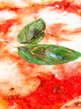 Çıtır çıtır bir hamurlu pizza, taze mozzarella, domates sosu ve mis kokulu fesleğen yaprağı içeren margherita pizzasının ayrıntılı görüntüsü, İtalyan mutfağının simgesel basitliğini ve lezzetlerini gözler önüne seriyor.
