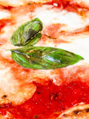 Çıtır çıtır bir hamurlu pizza, taze mozzarella, domates sosu ve mis kokulu fesleğen yaprağı içeren margherita pizzasının ayrıntılı görüntüsü, İtalyan mutfağının simgesel basitliğini ve lezzetlerini gözler önüne seriyor.