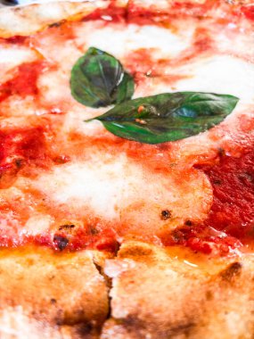 Çıtır çıtır bir hamurlu pizza, taze mozzarella, domates sosu ve mis kokulu fesleğen yaprağı içeren margherita pizzasının ayrıntılı görüntüsü, İtalyan mutfağının simgesel basitliğini ve lezzetlerini gözler önüne seriyor.