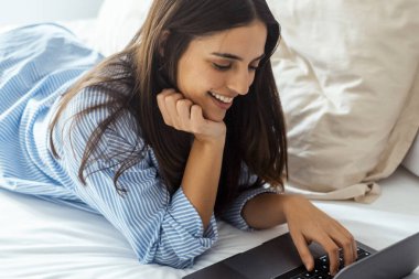 Yatak manifatura laptop yatan, erkek arkadaşıyla sohbet veya romantik mektubu mutlu kız kadın ileti web sörf, internet tarama kadın yatak odasında rahatlatıcı arkadaşlarınızla konuşurken gülümseyen