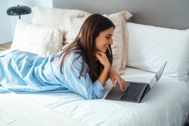 Yatak manifatura laptop yatan, erkek arkadaşıyla sohbet veya romantik mektubu mutlu kız kadın ileti web sörf, internet tarama kadın yatak odasında rahatlatıcı arkadaşlarınızla konuşurken gülümseyen