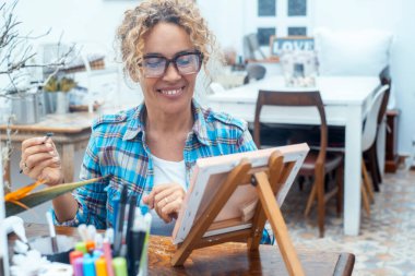 Geceleri evde saç boyaması yapan, sanat tutkusunu ifade eden, yaratıcılık, kişisel refah ve sanatsal hobilerin rahatlatıcı faydalarına odaklanmak için fırça ve renkler kullanan bir kadın.