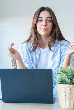 Günlük kot giymiş genç bir kadın ofis masasında oturmuş, sosyal medya stratejilerini ve serbest çalışma tekniklerini anlatırken, çevrimiçi özel ders ve içerik dijital iş dünyası yaratıyor.