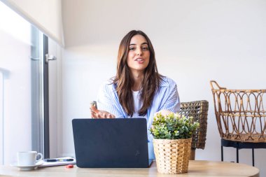 Günlük kot giyen, sosyal medya stratejilerini açıklayan, ofis masasında dizüstü bilgisayarın önünde el kol hareketi yapan, dijital işleri öğretmek için çevrimiçi özel ders yaratan bir kadın.