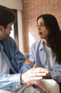 Evdeki kanepede oturan erkek ve kadın, ihanet ve sadakatsizlikten sonra ciddi ilişki zorluklarıyla yüzleşiyor, sevgi ve finansal stres kaybıyla mücadele ediyor ve gelecekleri hakkında birlikte zor kararlar veriyorlar.