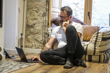 Adam bir dağ evinde tek başına oturuyor, internette gezinmek ve sosyal medyada gezinmek için dizüstü bilgisayarını kullanıyor, dağlarda gündelik hayattan kopuk bir şekilde tatildeyken huzurlu bir rahatlama anı yaşıyor.