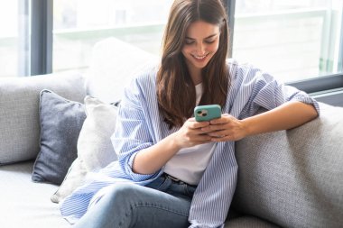 Milenyum kızı elinde akıllı telefonuyla evdeki kanepede oturuyor, sosyal medyada geziniyor, arkadaşlarıyla mesajlaşıyor, dijital servislere abone oluyor, web sayfalarına göz atıyor ve çevrimiçi bilgi okuyor.