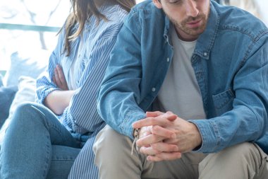 Milenyum çifti evdeki bir kanepede oturuyor, sırtını dönüyor, birbirini görmezden geliyor, ilişki sorunlarını tartışıyor, mali stres, güven sorunları, aldatma, duygusal kopukluk ve iş kaybı.