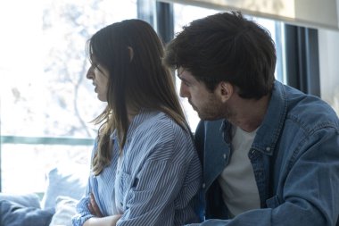 Oturma odasında birbirlerinden uzak oturan bunalımlı erkek ve kadın ilişki sorunları, güven sorunları, aldatma, maddi baskı ve duygusal sıkıntı ile boğuşuyorlar.