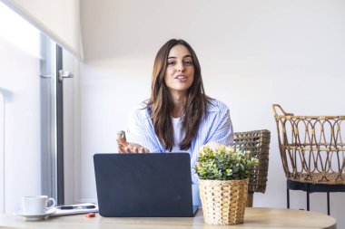 Günlük kot giyen, sosyal medya stratejilerini açıklayan, ofis masasında dizüstü bilgisayarın önünde el kol hareketi yapan, dijital işleri öğretmek için çevrimiçi özel ders yaratan bir kadın.