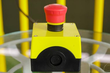 Bir sistemi çalıştırmak için bir cihaz. Fotoğrafta üstünde kırmızı düğme olan sarı bir kutu var..